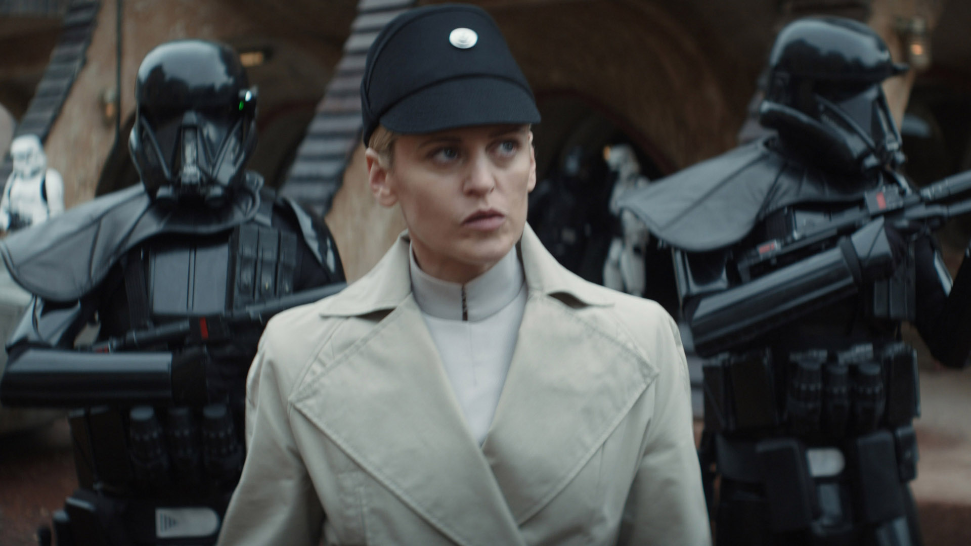 Dedra Meero looks at something off camera as she walks flanked by two shock troopers in Andor on Disney Plus