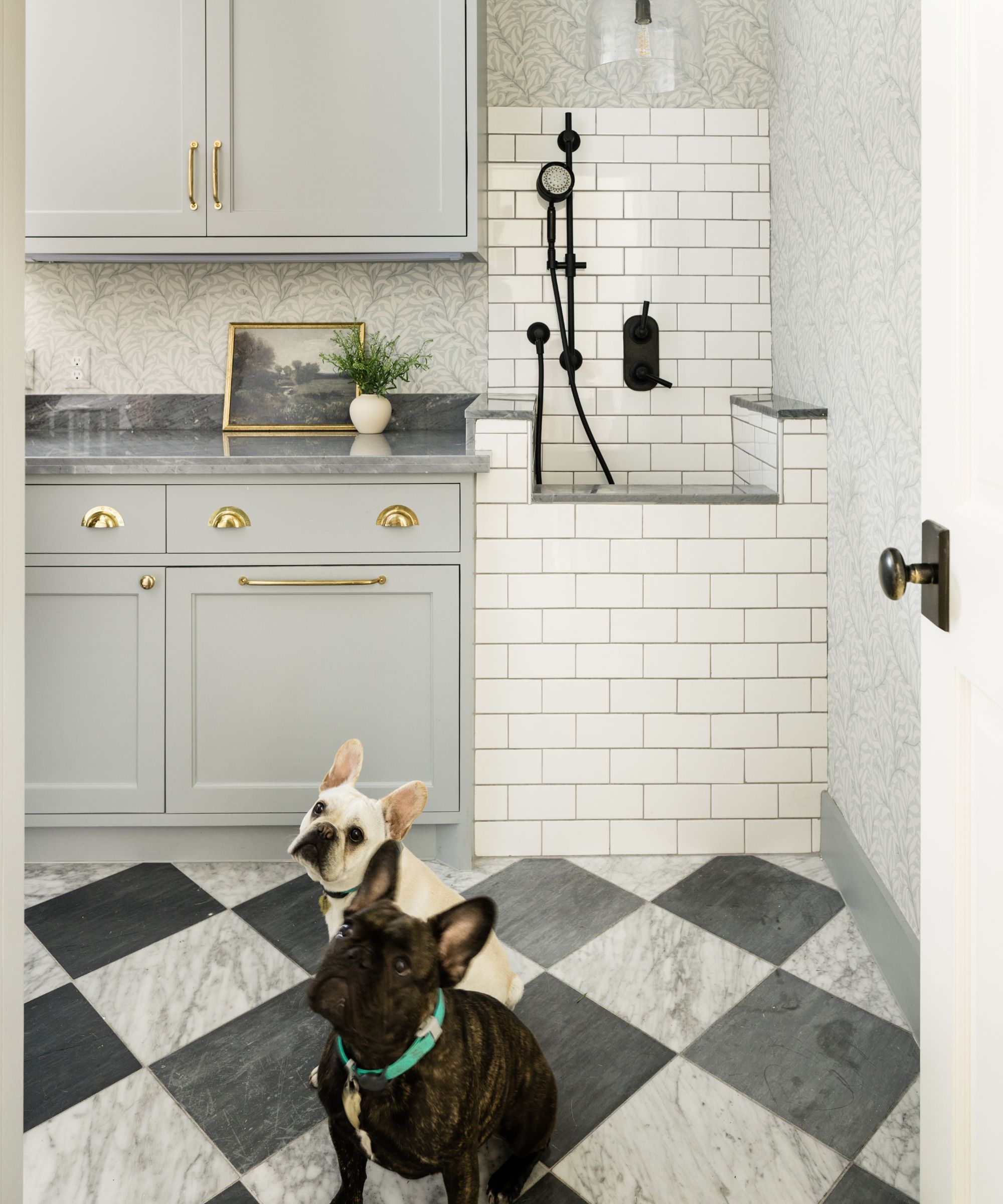 a boot room designed with a custom white tiled dog wash station with checkerboard floors