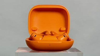 Beats Powerbeats Pro 2 in orange in the charging case with the lid open to reveal the earbuds
