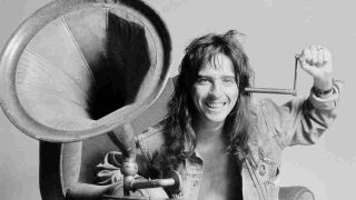 Alice Cooper posing for a photograph with a gramophone in 1974