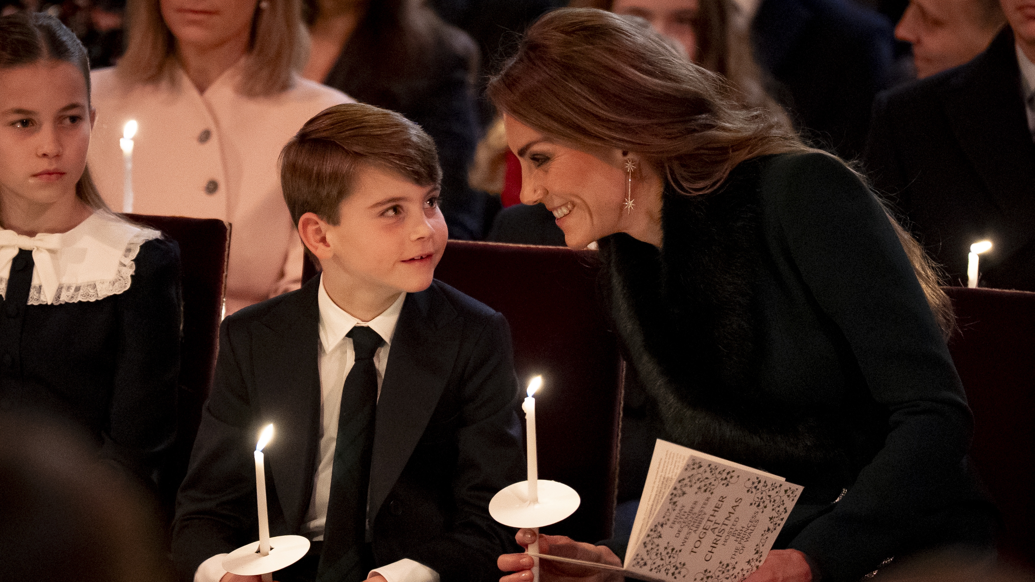 Princess Charlotte, Prince Louis and Catherine, Princess of Wales smile and sit together holding candles during the Together At Christmas carol service at Westminster Abbey on December 5, 2025