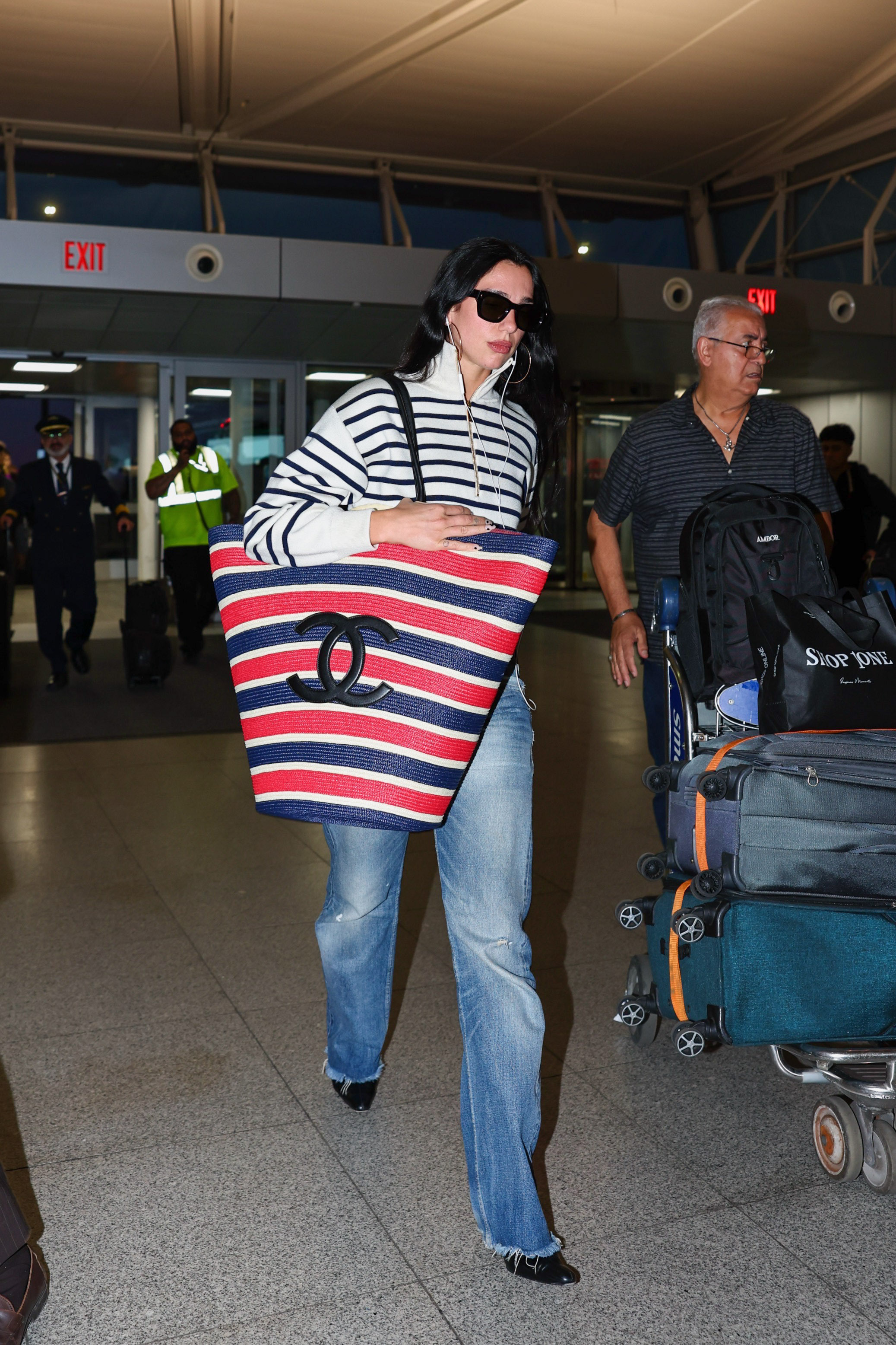 Dua Lipa arrived at the airport with Chanel's new oversized beach bag to match her coastal striped quarter-zip