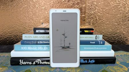 Boox Palma 2 Pro ereader in front of a stack of books