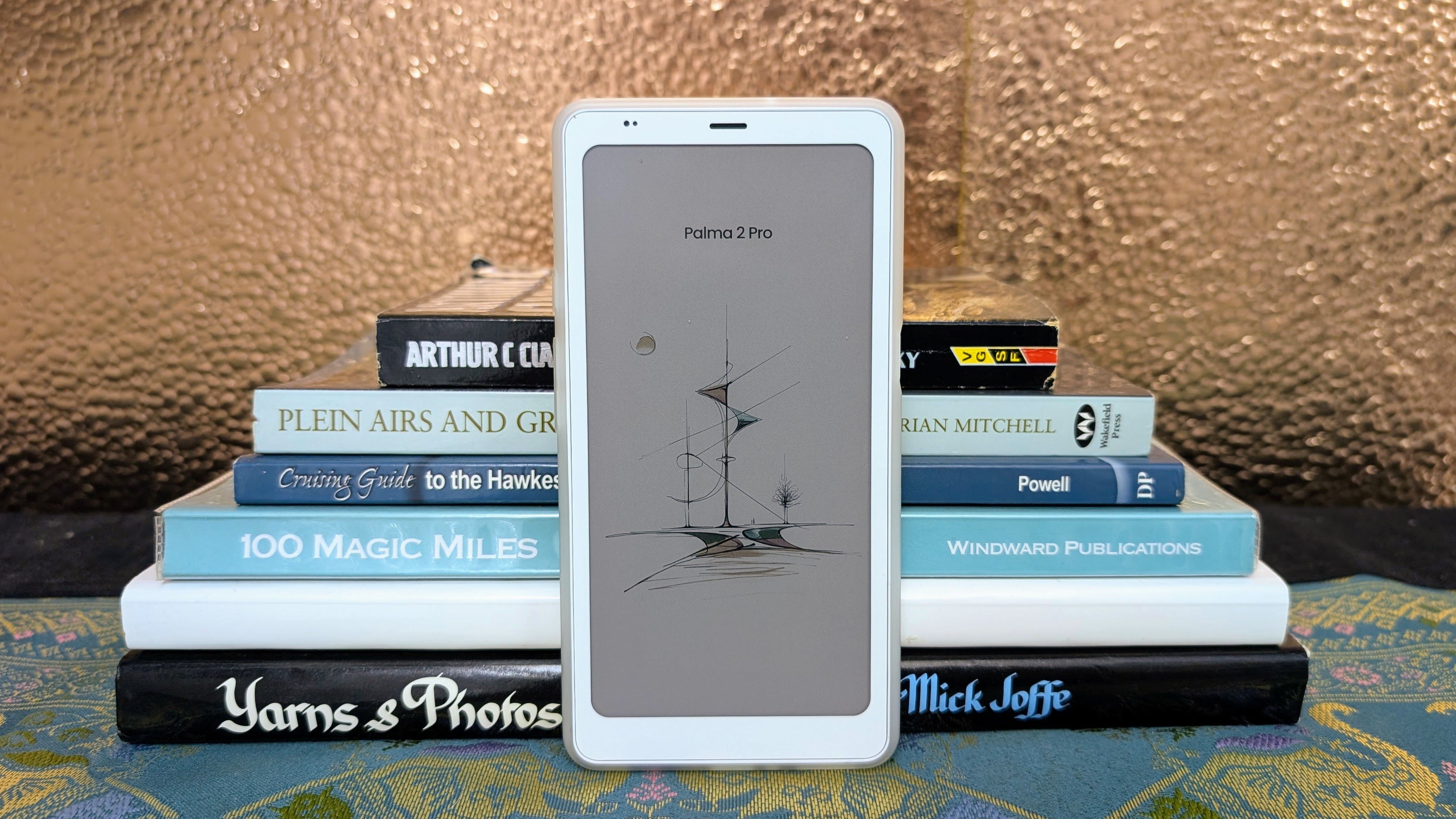 Boox Palma 2 Pro ereader in front of a stack of books
