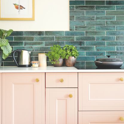 KItchen with pink cupboards, a white worktop, and green tiles on the wall