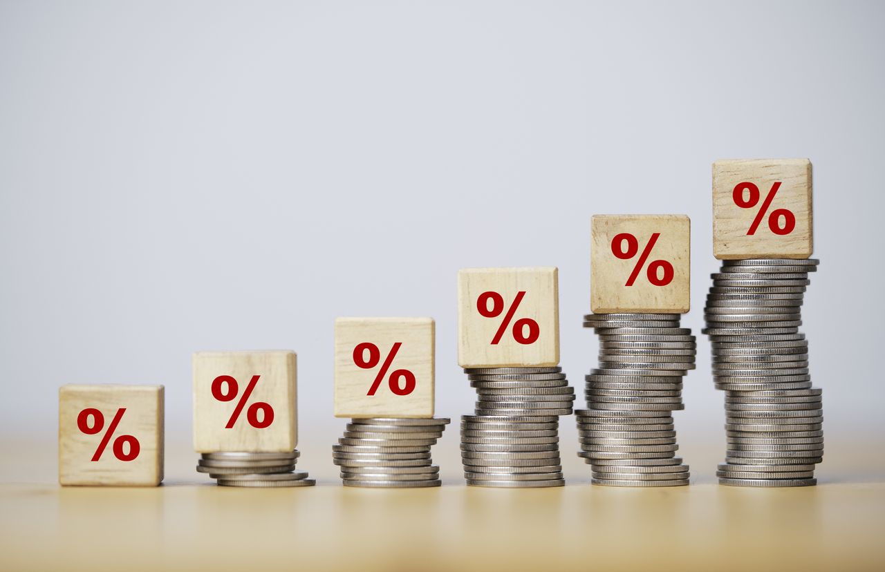 Percentage sign print screen on wooden cube block which lay down on increasing coins stacking for interest rate and business profit growth concept. 