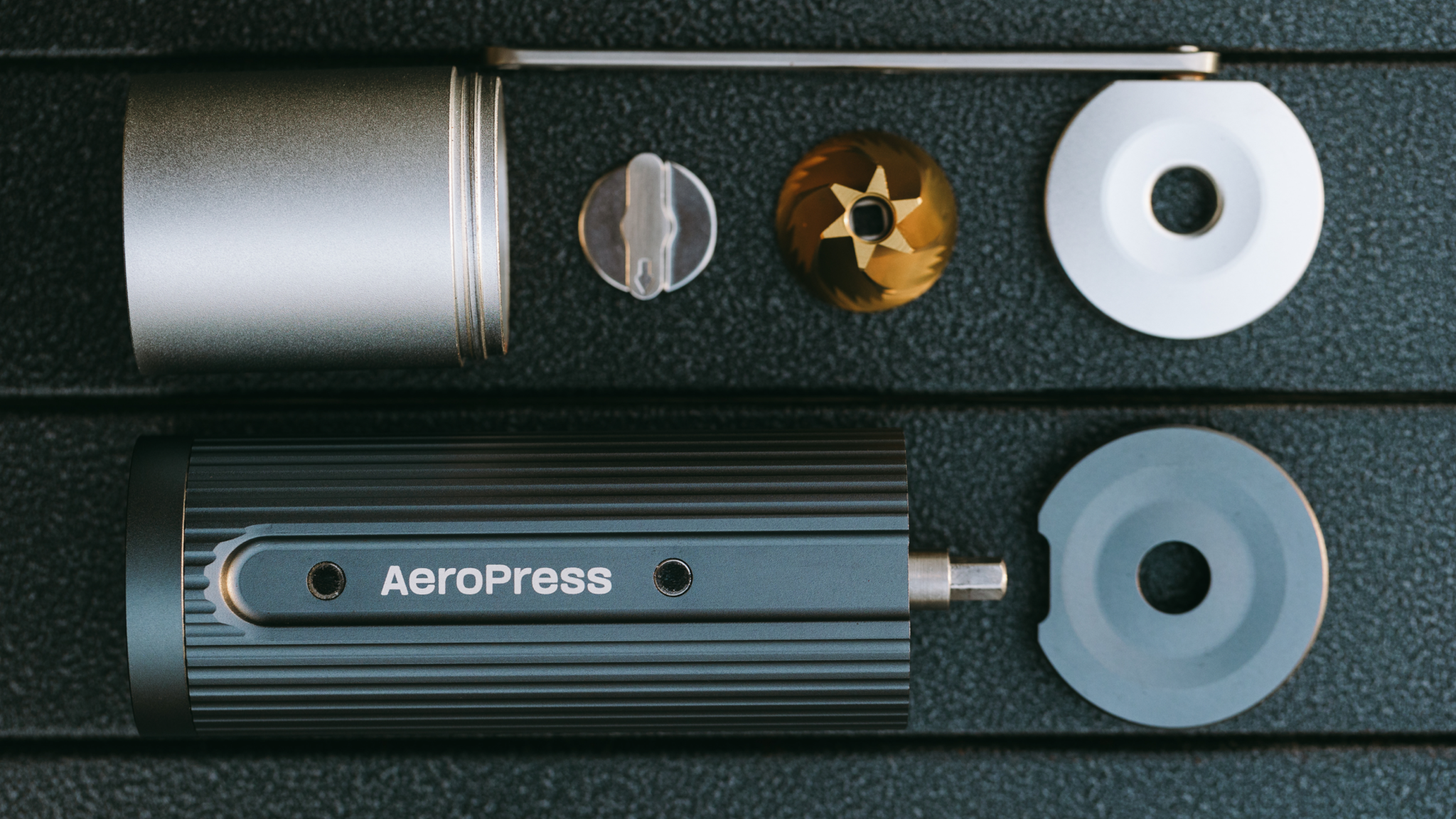 AeroPress Manual Coffee Grinder taken apart and set out on a black surface