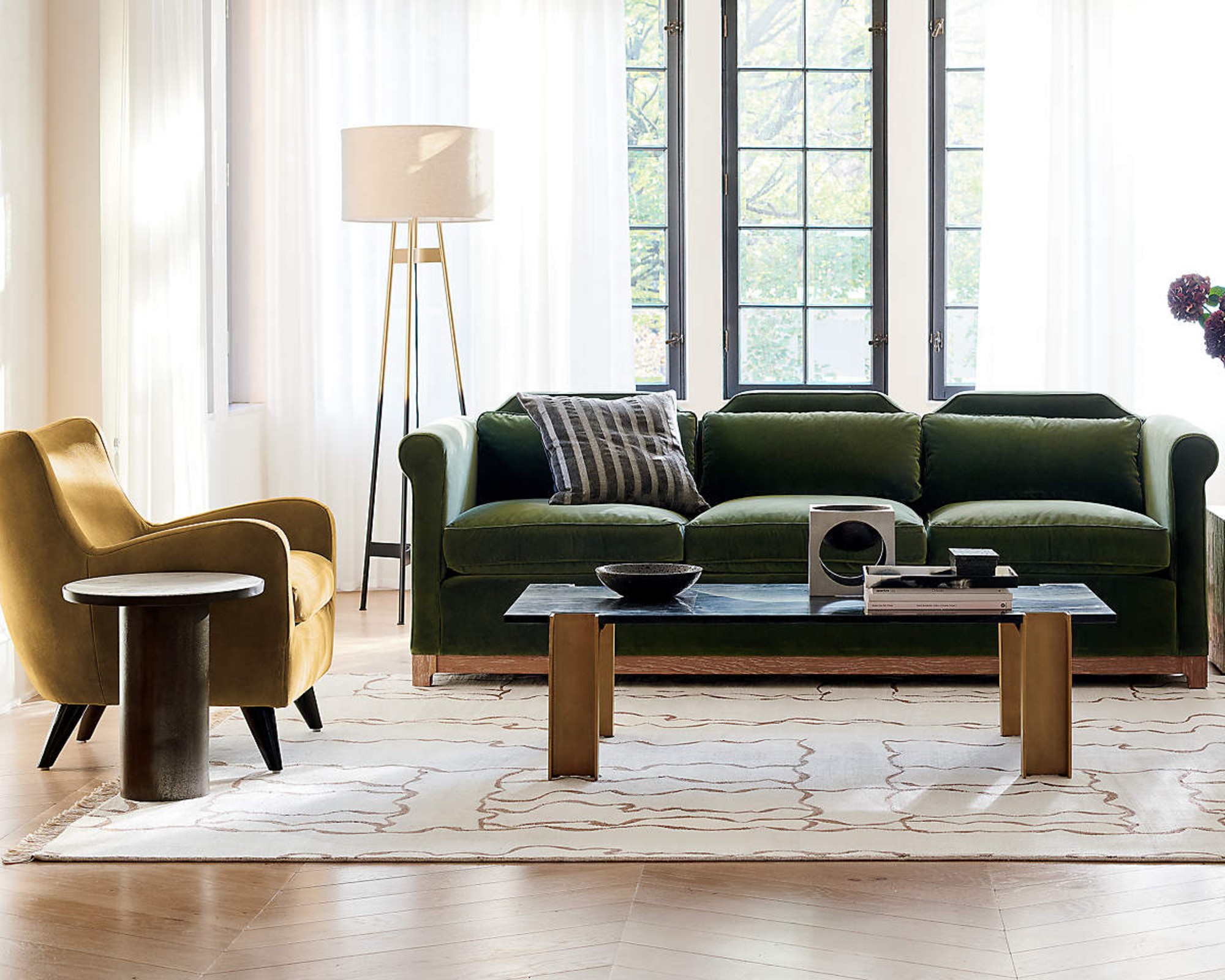 A classically styled green velvet sofa with scroll arms and wooden base