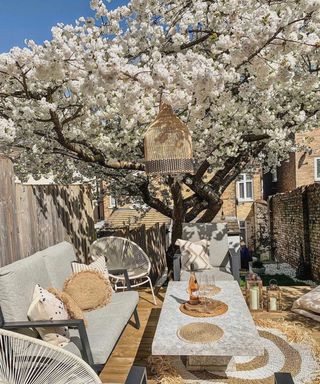 A deck idea with cherry blossom tree, marble effect table and exposed brick wall