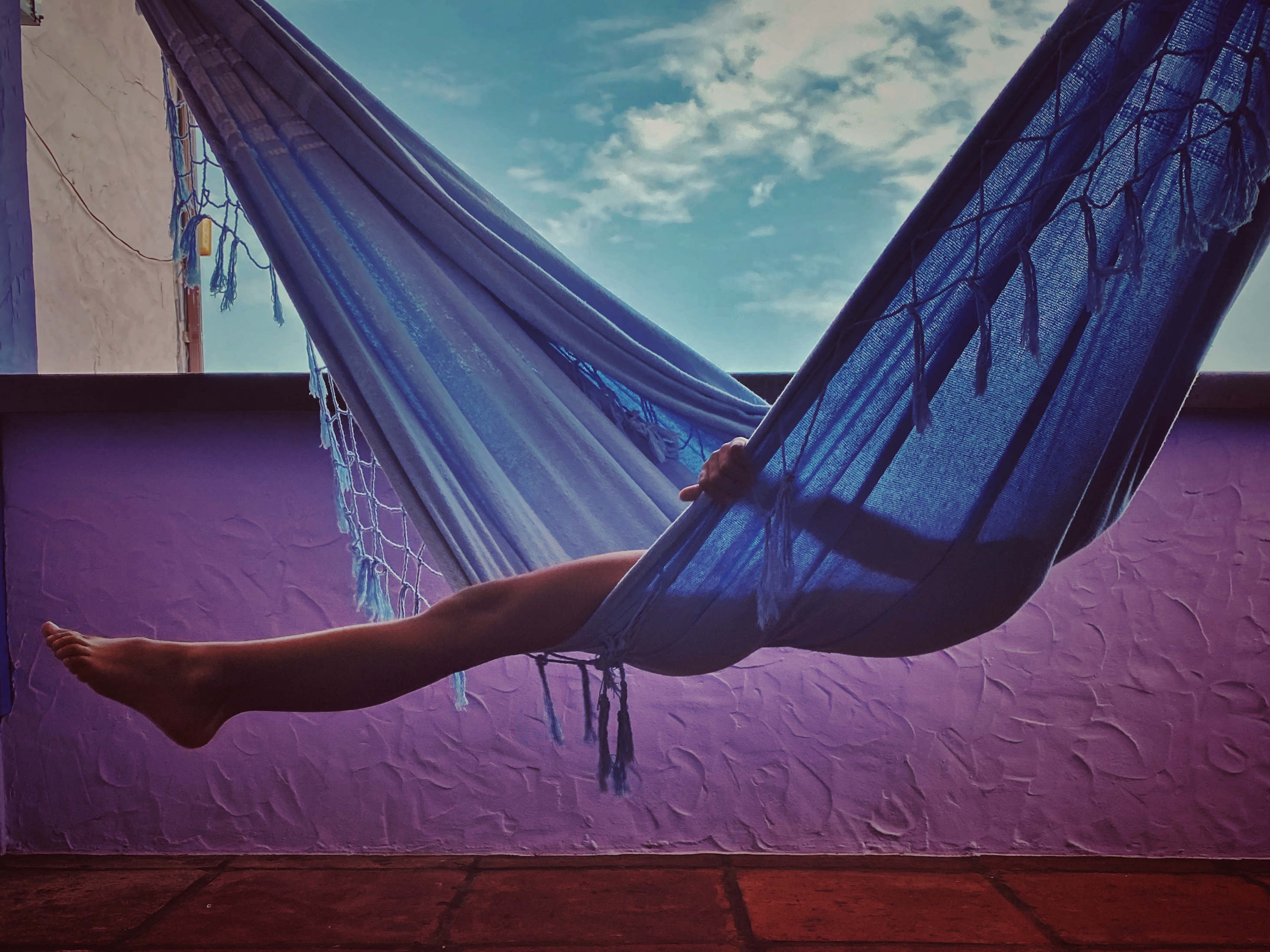 A child swinging in a blue hammock in front of a purple wall