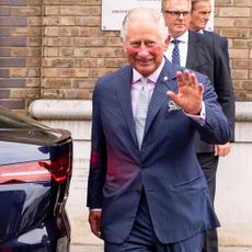 King Charles waving next to a Jaguar