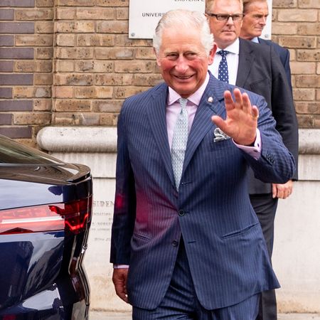 King Charles waving next to a Jaguar