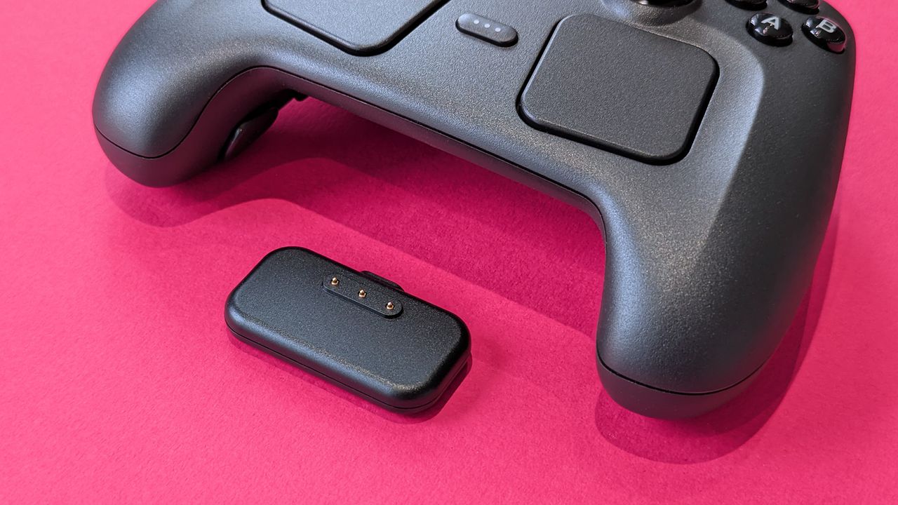 Charging puck and Valve Steam Controller (2026) displayed on a magenta card background