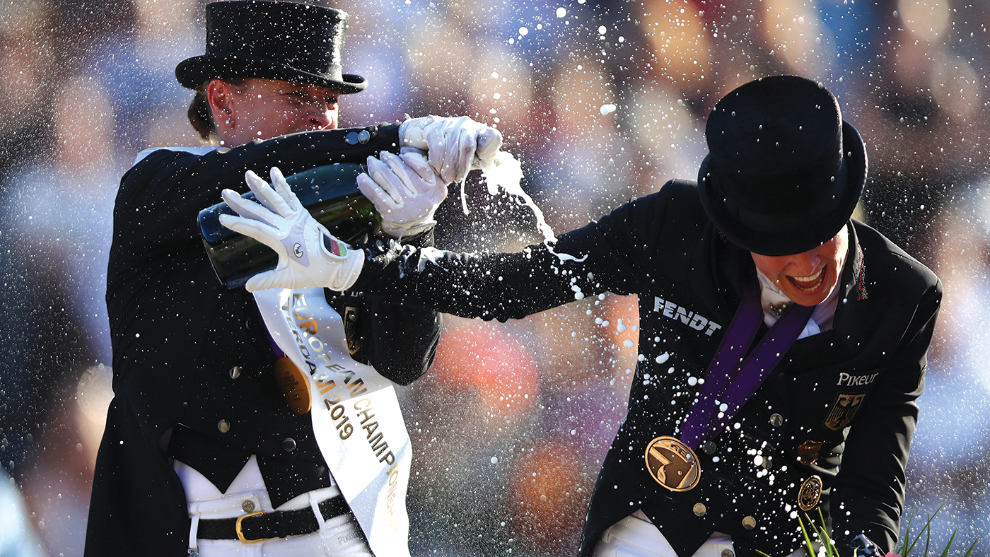 ROTTERDAM, NETHERLANDS - AUGUST 24: Isabell Werth of Germany riding Bella Rose celebrates winning the gold medal by spraying champagne on third place Jessica von Bredow-Werndl of Germany riding TSF Dalera BB on Day 6 in the Grand Prix Freestyle, Longines FEI Dressage European Championship presented by Rabobank at Foundation CHIO on August 24, 2019 in Rotterdam, Netherlands. (Photo by Dean Mouhtaropoulos/Getty Images for FEI)