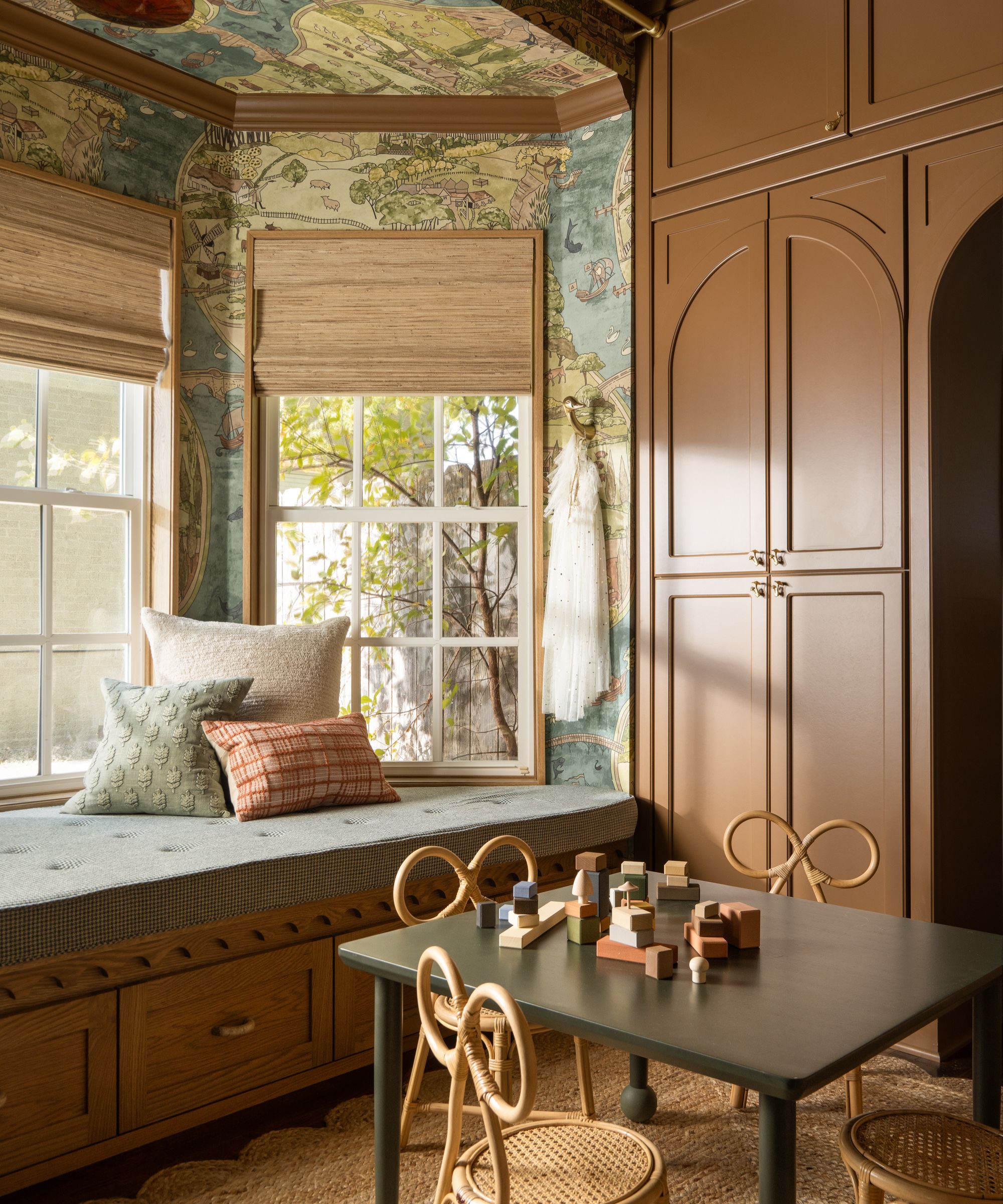 Nursery with wood cabinets, map wallpaper, window seat and table