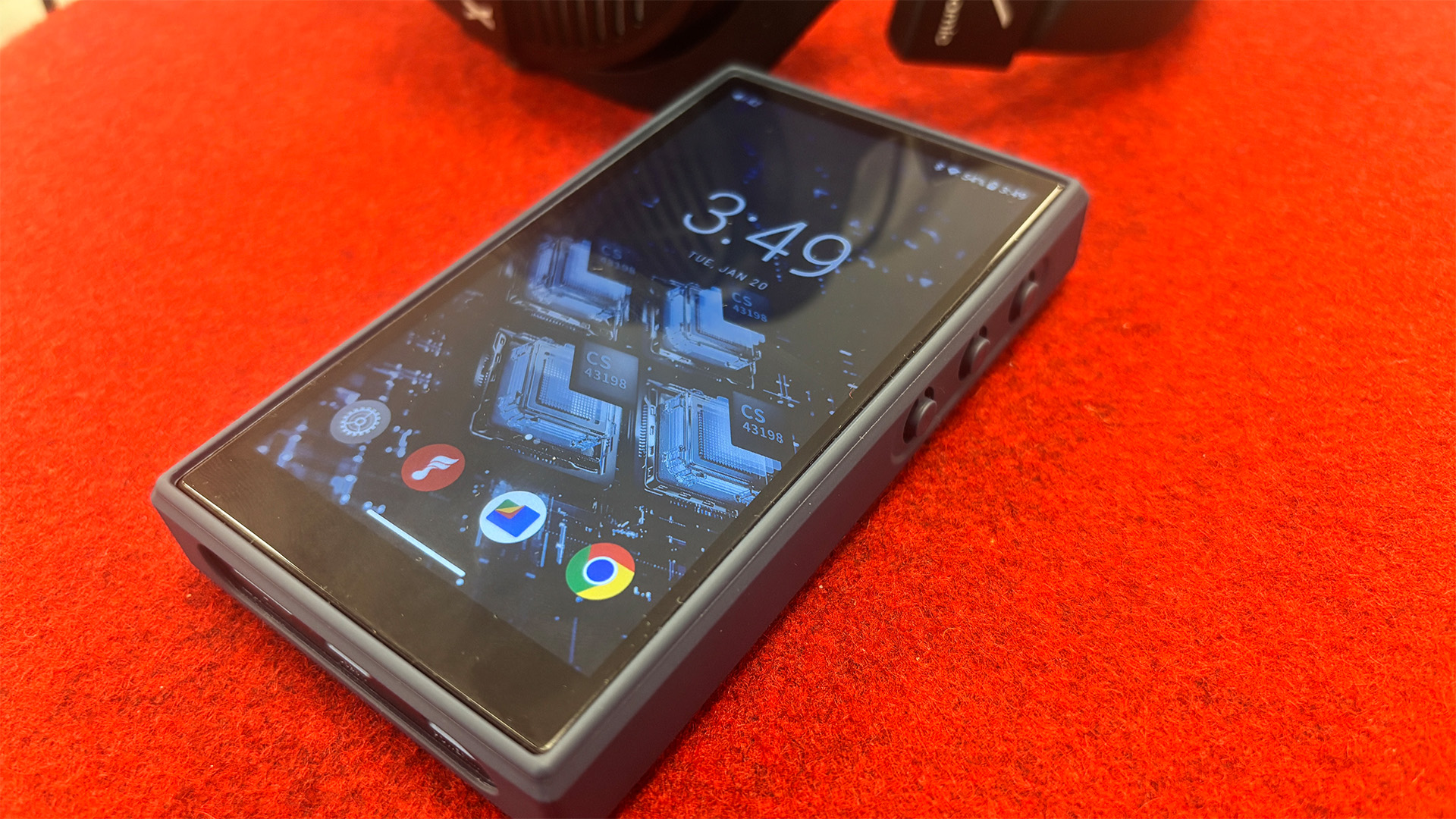 FiiO M21 portable music player on red surface, showing screen with Android OS