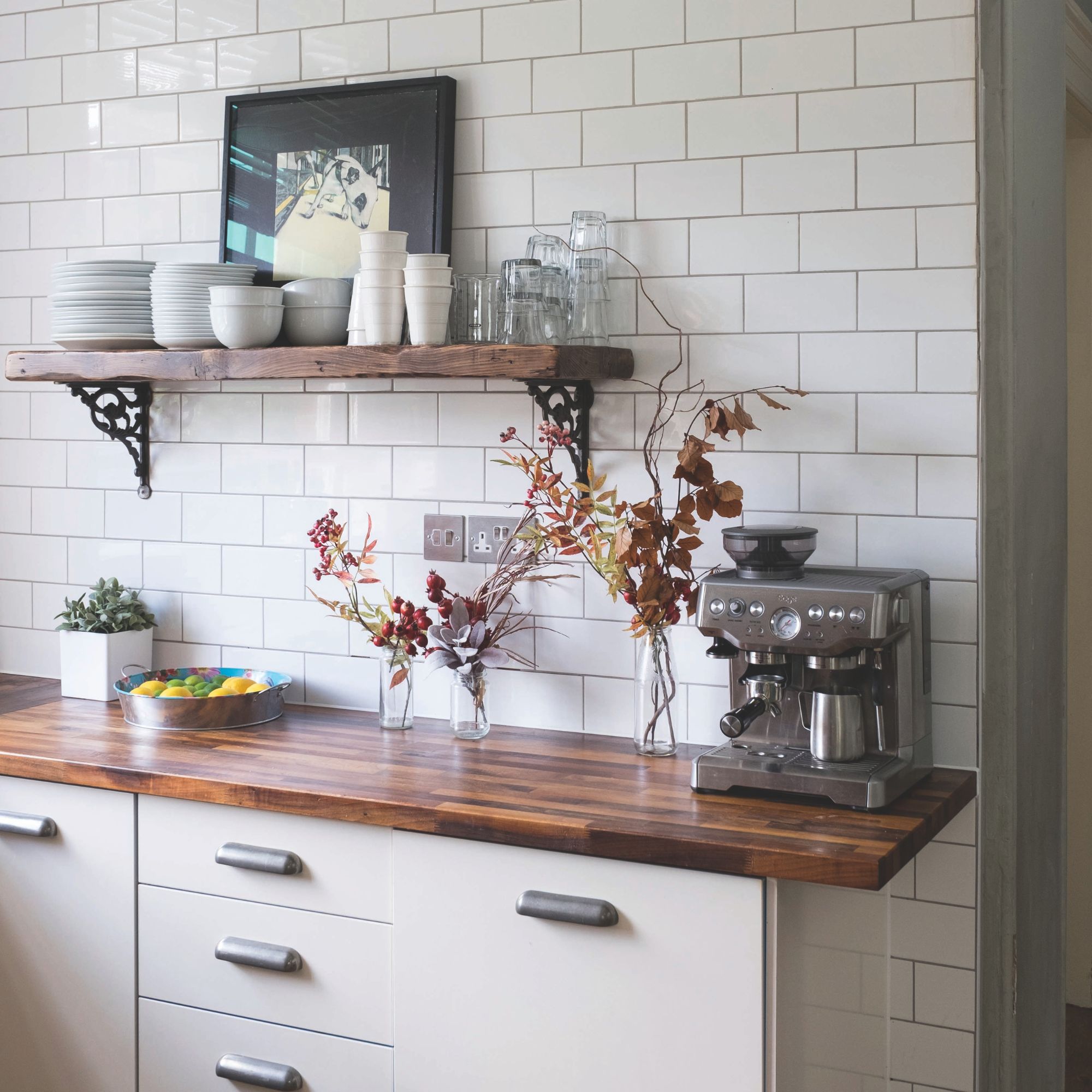 Kitchen worktop area with tiled wall and a wooden worktop, and a coffee machine on it