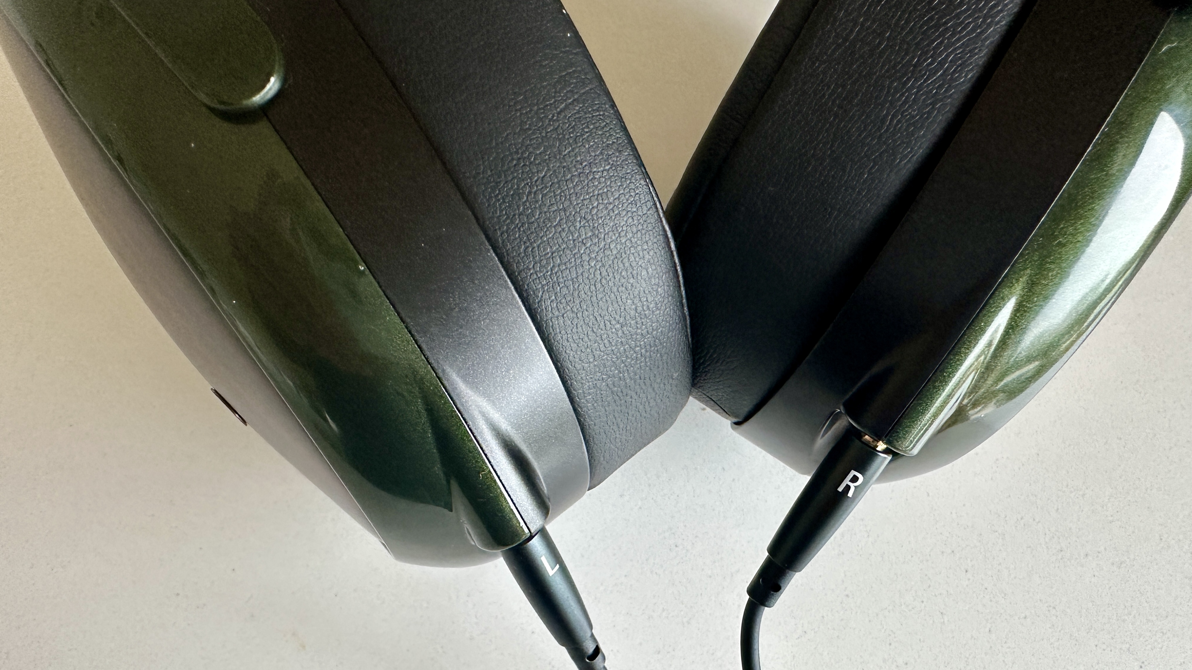 Meze Audio Strada headphones with wooden ear cups, in close-up and with their case and cables visible, on a white table