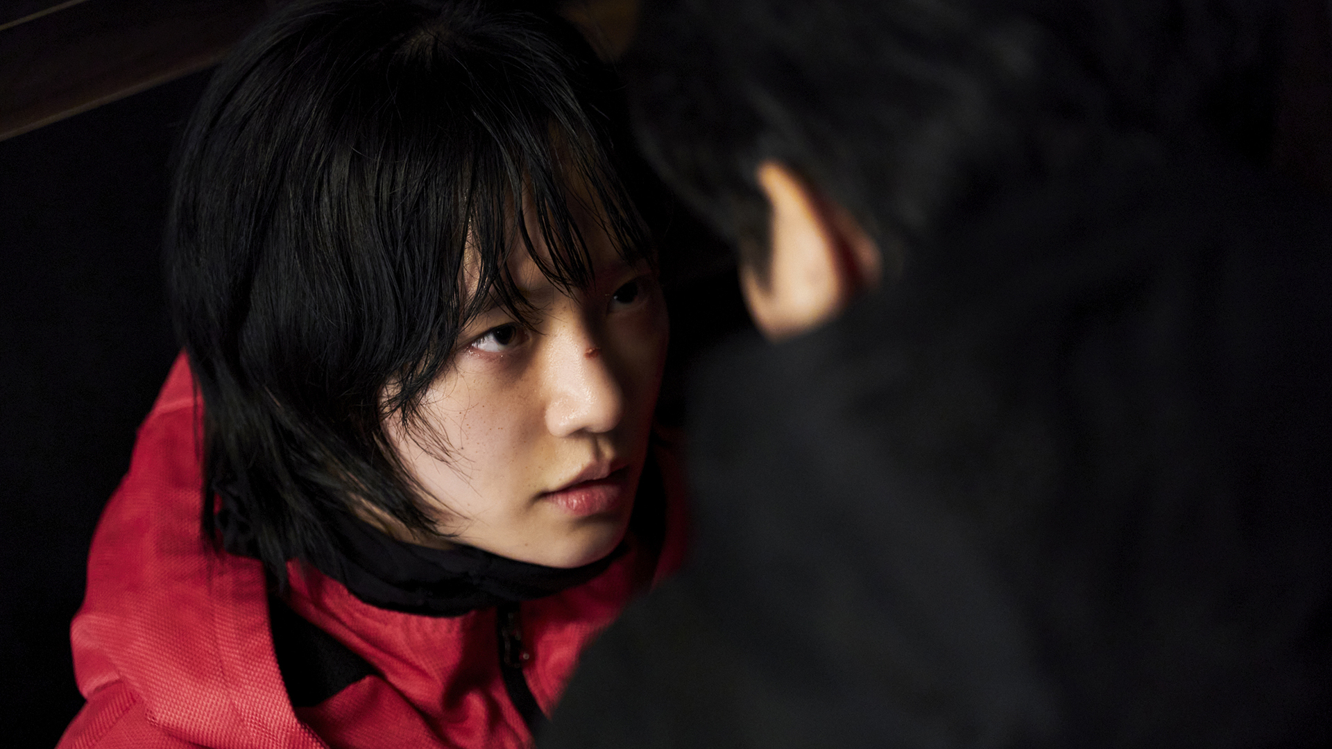 A close up of No-eul wearing a pink jumpsuit and looking at someone in Squid Game season 3