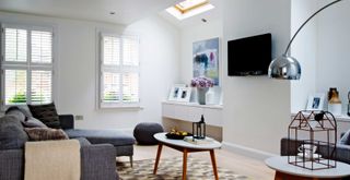 white living room with small skylight and flatscreen tv on the wall