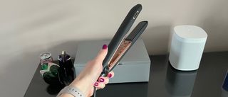 The Panasonic EH-HS99 hair straightener being held in a hand above a glass countertop