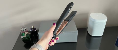 The Panasonic EH-HS99 hair straightener being held in a hand above a glass countertop
