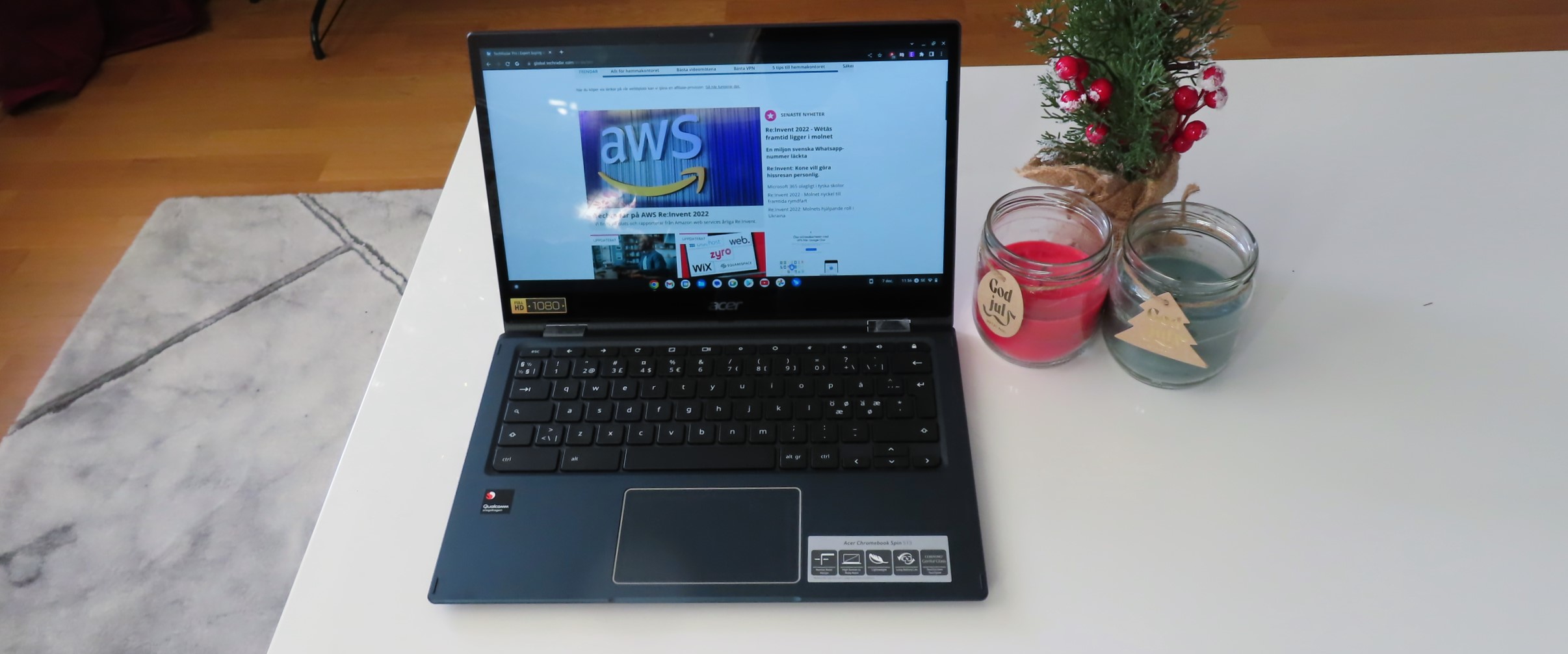 En Acer Spin 513 står öppnad på ett vitt vardagsrumsbord bredvid ett block och ett par ljus.