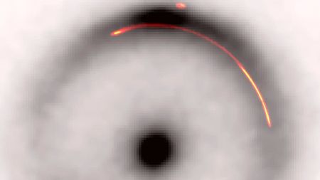 A black and white image of an Einstein ring with a red a yellow arc highlighted within its halo
