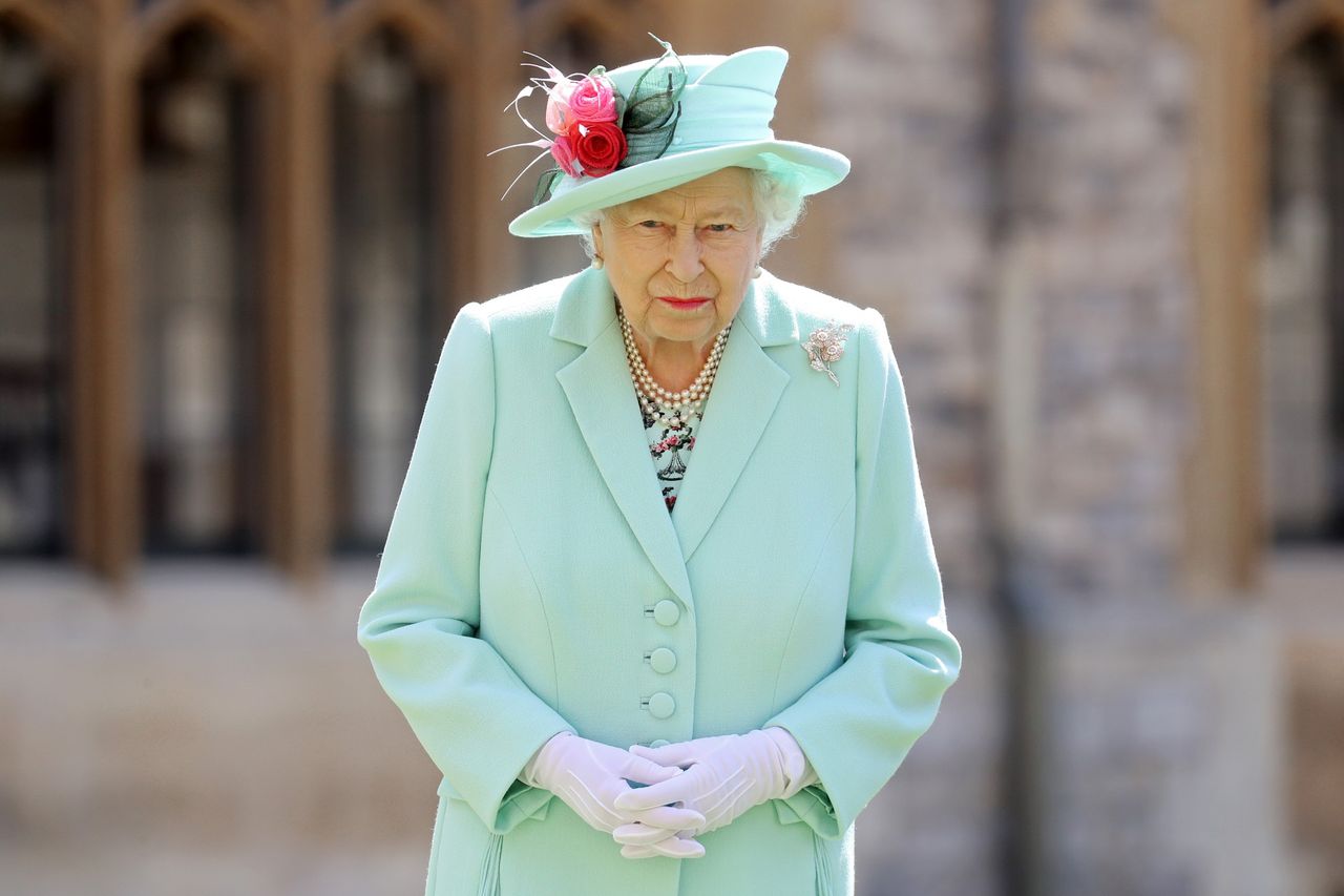 Queen Elizabeth II poses after awarding Captain Sir Thomas Moore with the insignia of Knight Bachelor at Windsor Castle on July 17, 2020 in Windsor, England