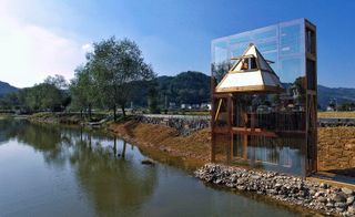 Exterior view of The Mirrored Sight, by Li Hao, Guizhou, China, seen next to river and under blue skies
