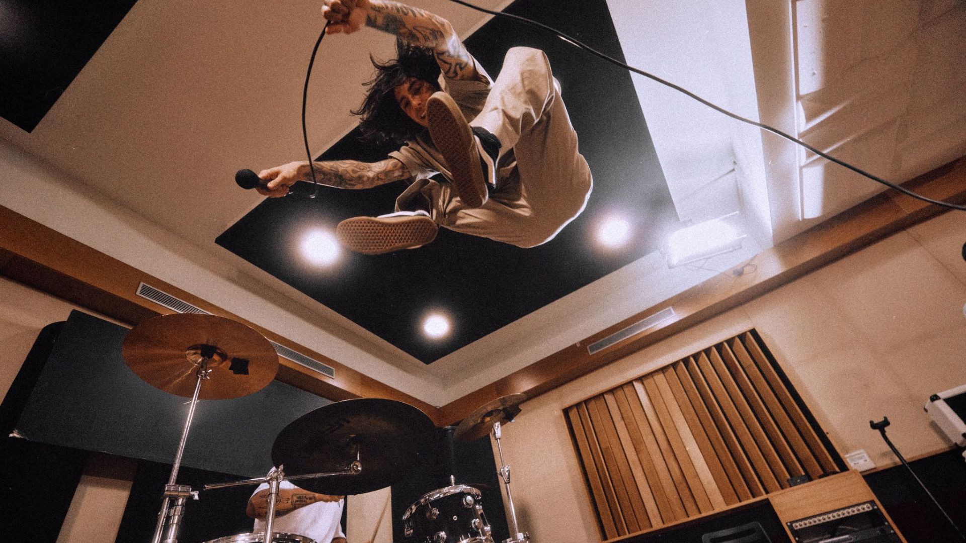 an image of an artist mid-jump in a recording studio whilst wearing the Dickies 247 trousers in desert sand