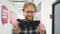 Mike Harris holding a Nikon ZR with 40mm lens in an office building