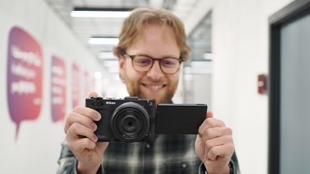 Mike Harris holding a Nikon ZR with 40mm lens in an office building