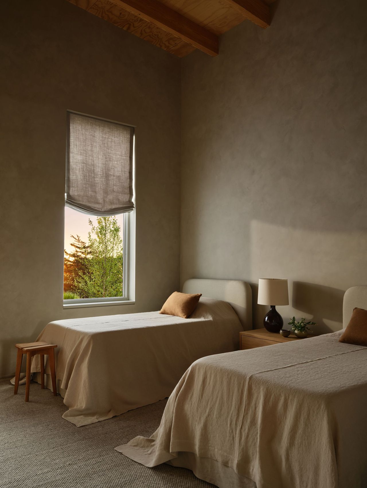 bedroom with two twin beds with off white sheets and venetian plastered walls