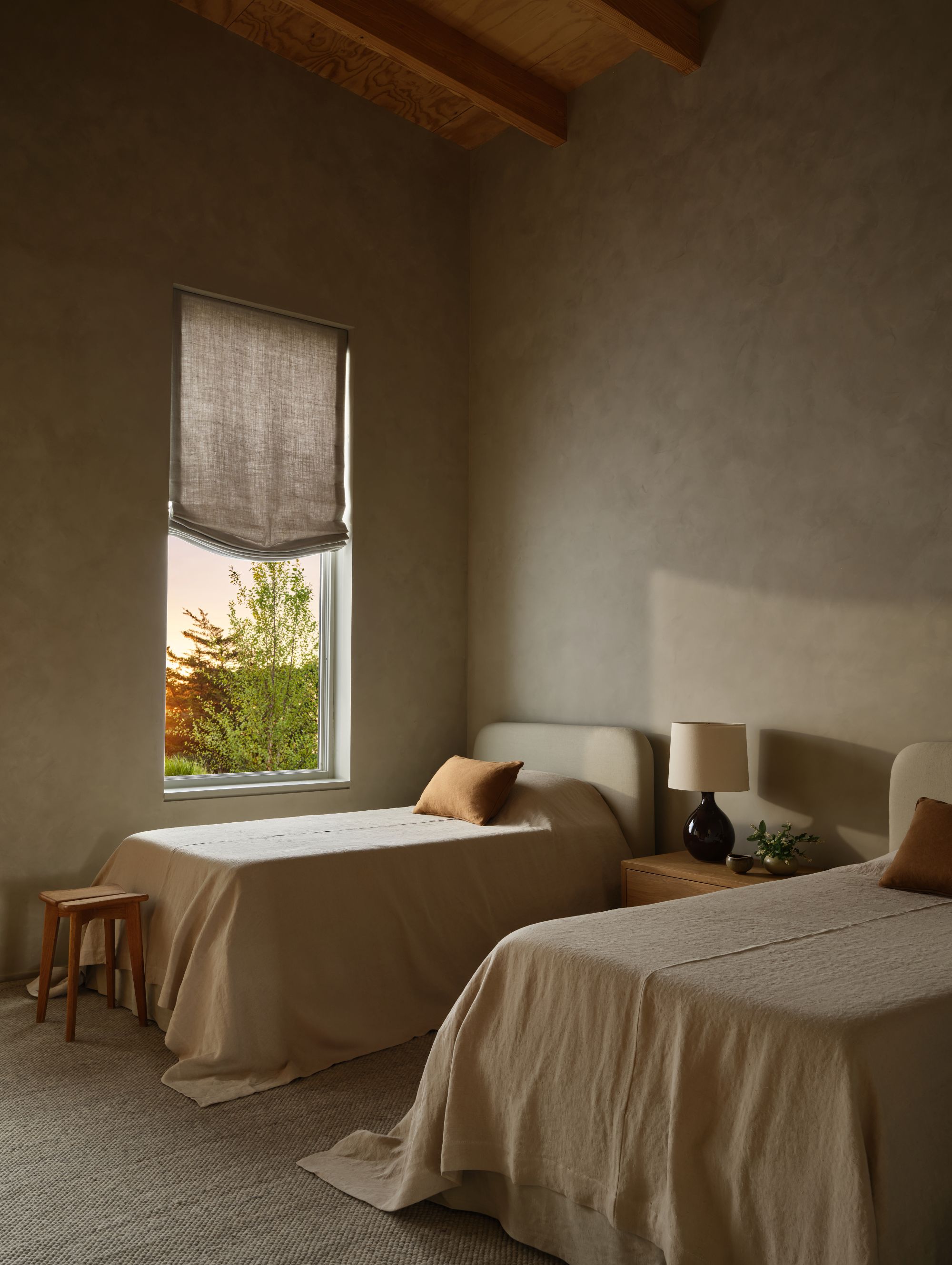 bedroom with two twin beds with off white sheets and venetian plastered walls