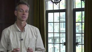 University professor talking in front of window