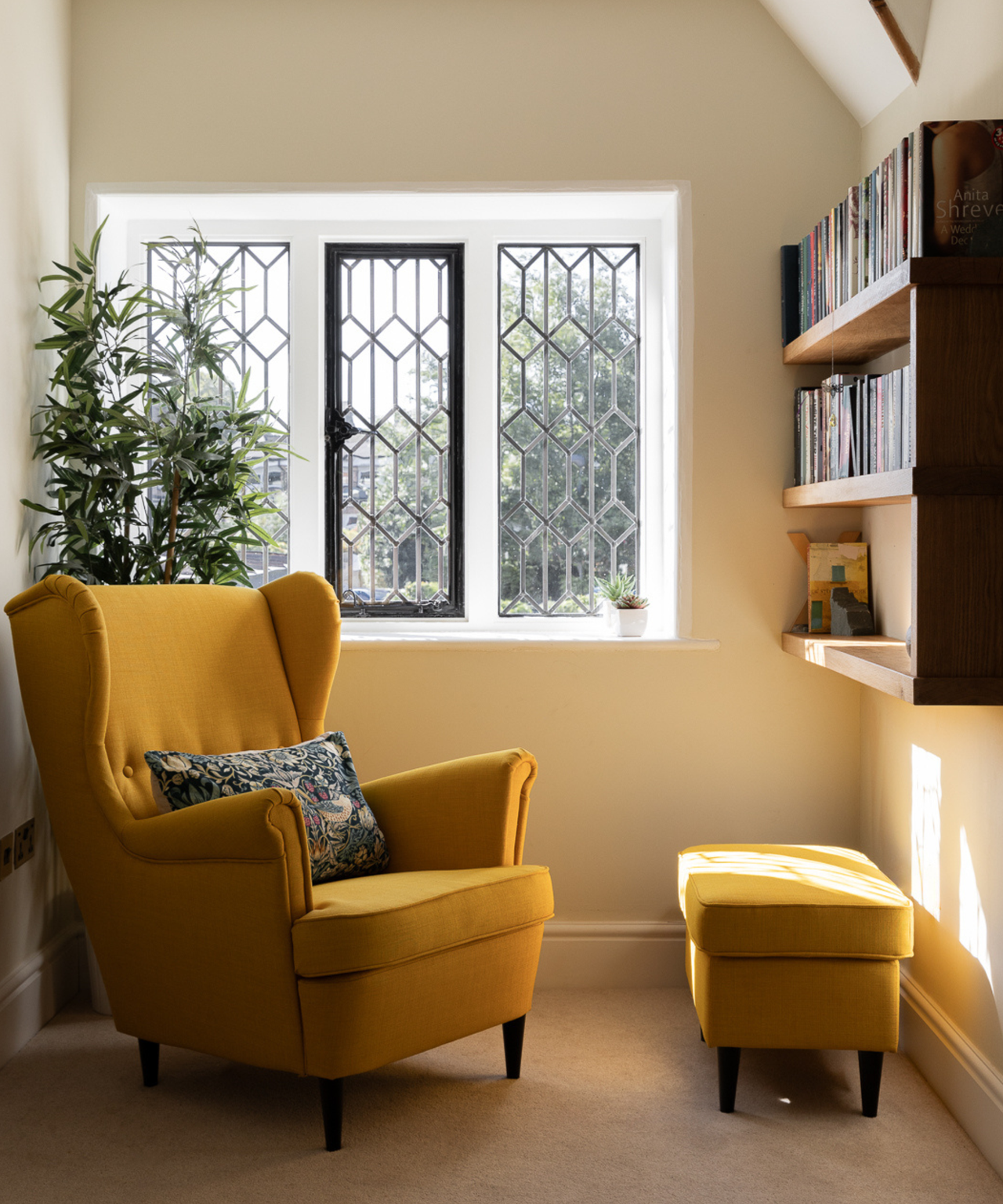 reading nook area with book shelf and mustard chair and foot stall