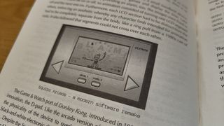 retro computers; an old Nintendo handheld game is on a book's page
