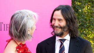 Keanu Reeves and Alexandra Grant smiling on the red carpet