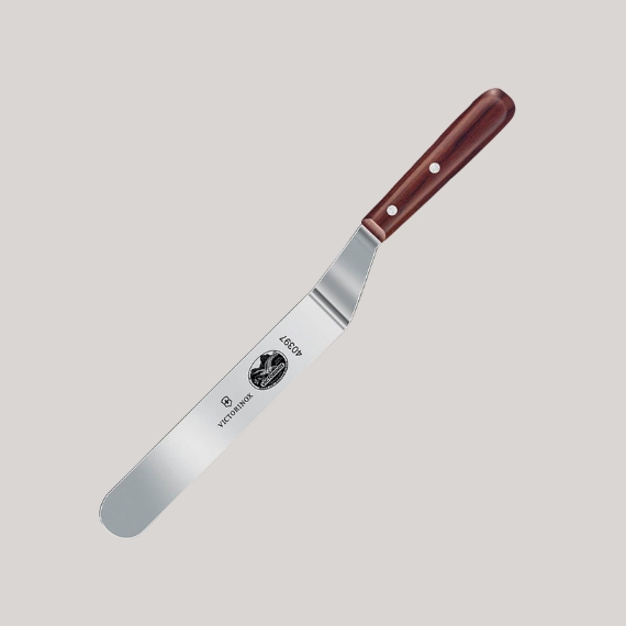 An angled palette knife in stainless steel and brown wood sits against a pale grey background.