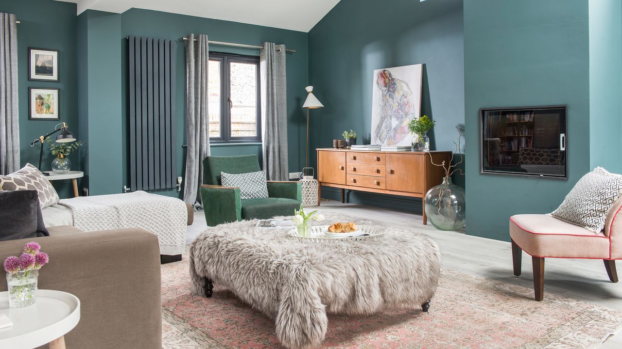 Modern blue living room with fur covered footstool and grey contemporary windows