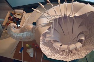 A photograph of a flower shaped environment model made out of paper from the game.