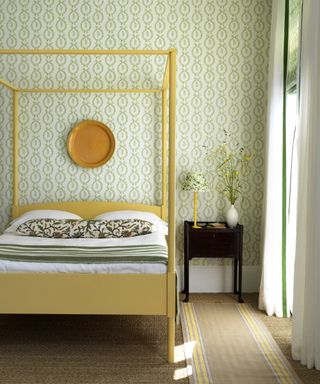 Simple bedroom ideas featuring green patterned wallpaper and a yellow four poster bed.
