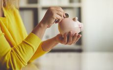 Woman inserts a coin into a piggy bank, toned image