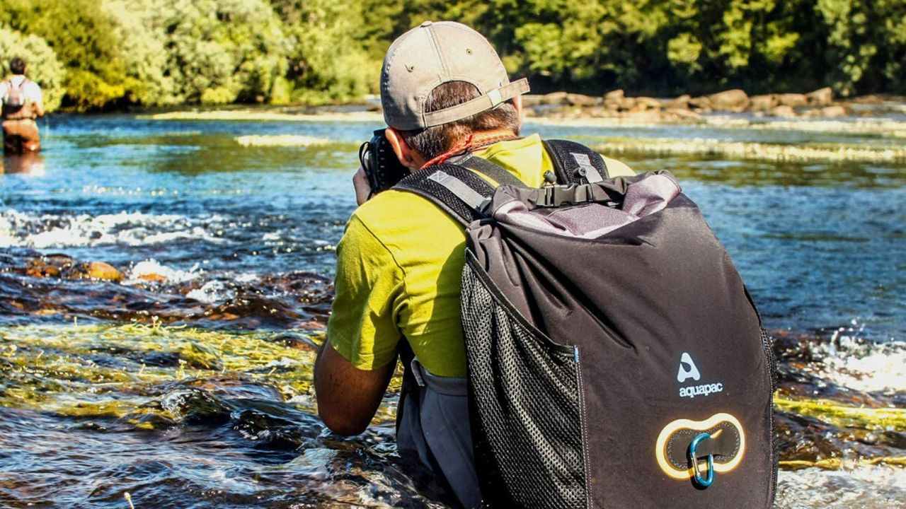 Man wearing Aquapac 25 litre Wet &amp; Dry backpack while wading through a river