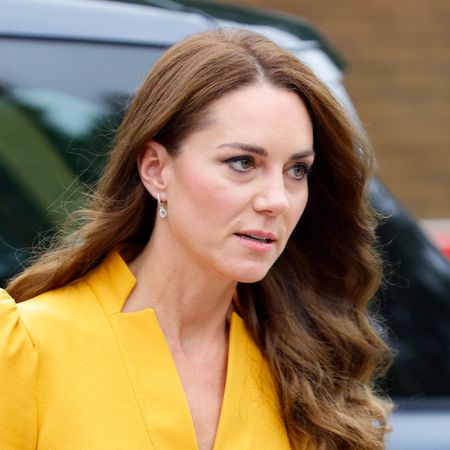 Kate Middleton has long, wavy brunette hair and wears a bright yellow dress with puffy sleeves