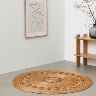 A round jute rug sat in the middle of a concrete floor 