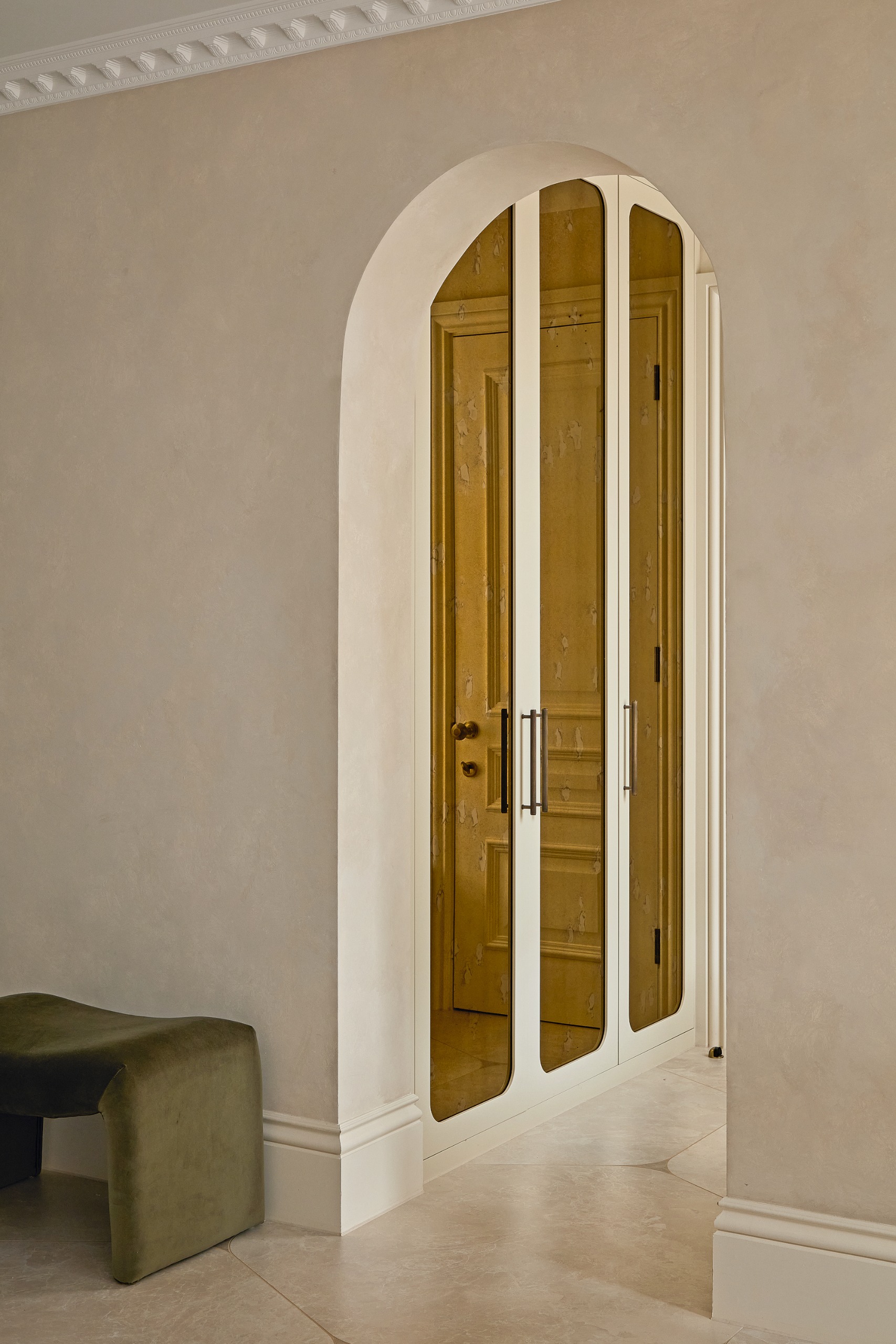 Shot to wardrobe room with amber glass wardrobe doors and a green velvet bench