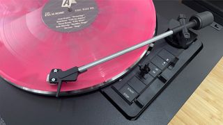 Rekkord Audio F110 turntable with pink vinyl showing tone arm and controls