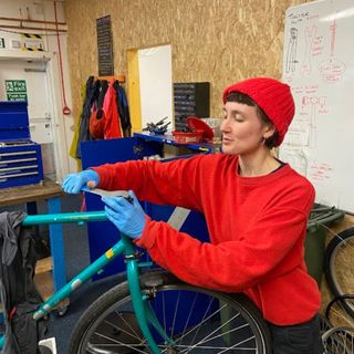 Woman works on the front end of a bike